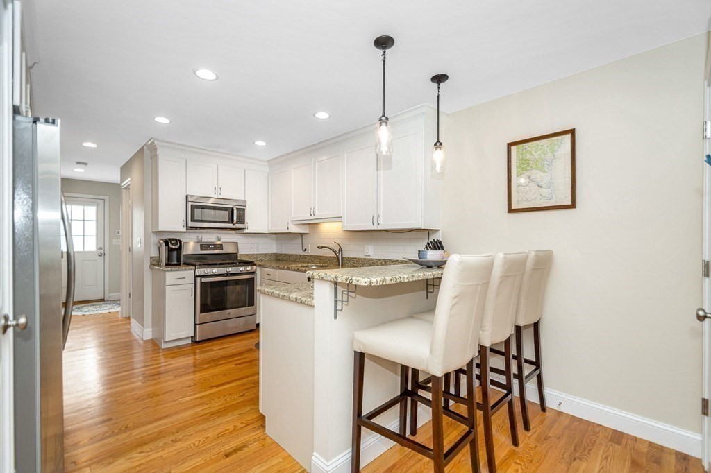 2a Ferry Road, Unit B Salisbury, MA 01952 - Photo 3 of 22 a kitchen with stainless steel appliances granite countertop a stove top oven a refrigerator a sink and a dining table with wooden floor