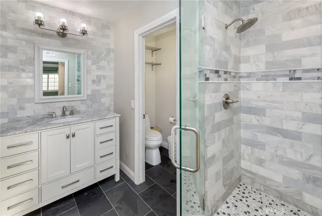 a bathroom with a granite countertop sink toilet and shower