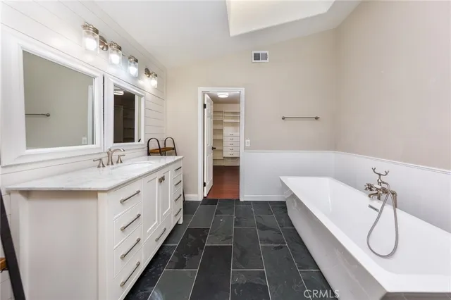 a spacious bathroom with a double vanity sink a large mirror and a bathtub