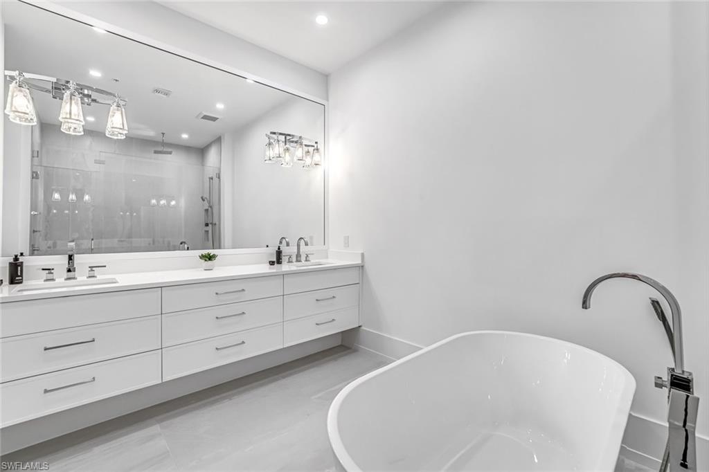 201 8th Street South, Unit 308 Naples, FL 34102 - Photo 16 of 28 a spacious bathroom with a double vanity sink a mirror and a bathtub