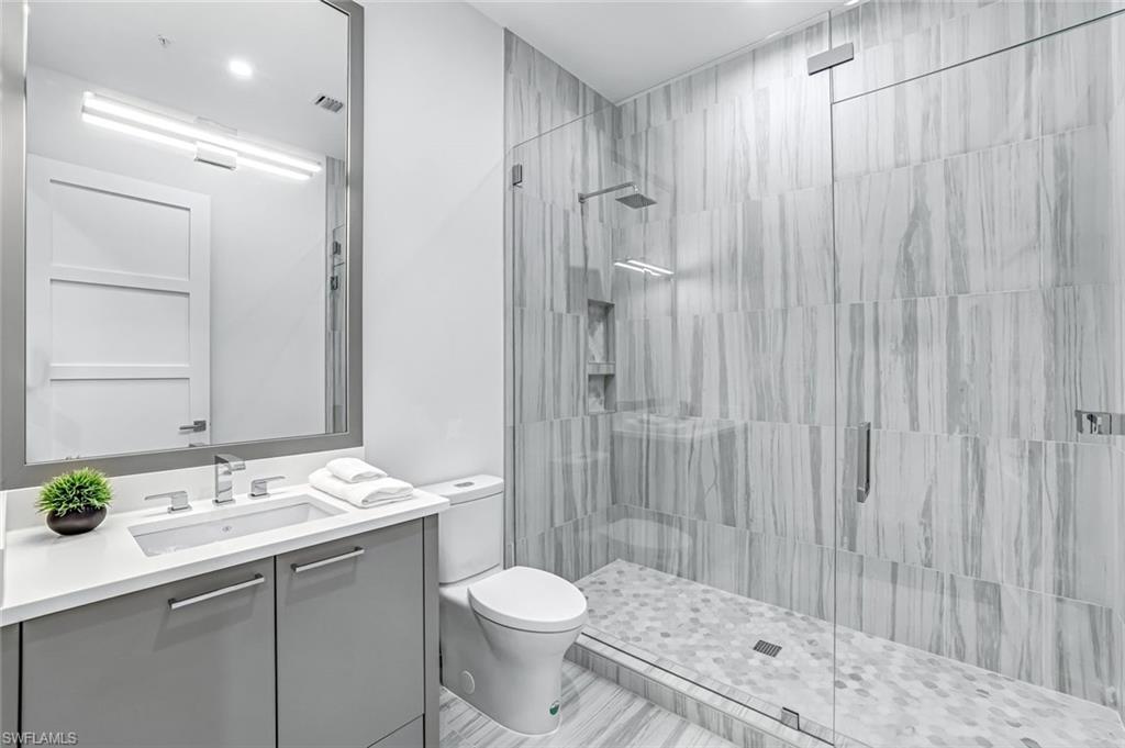 201 8th Street South, Unit 308 Naples, FL 34102 - Photo 21 of 28 a bathroom with a double vanity sink toilet and shower