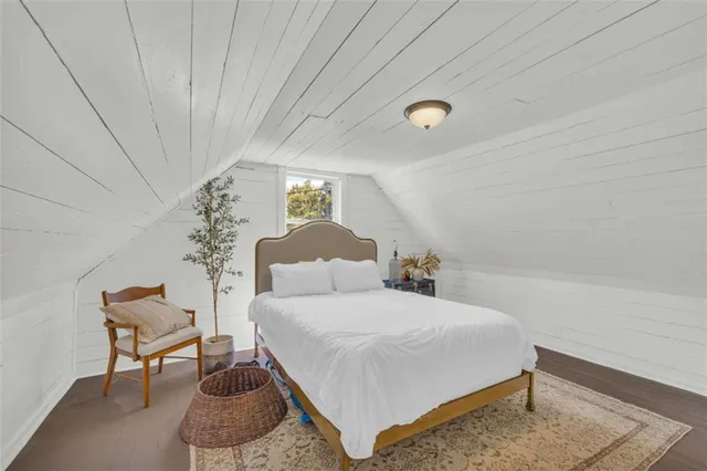 a bedroom with a bed and a potted plant on the dresser