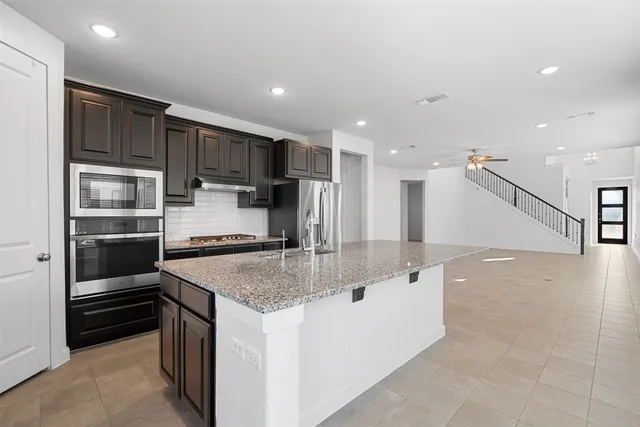 a kitchen with stainless steel appliances granite countertop a sink a stove and a refrigerator