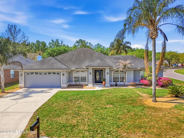 a front view of a house with a yard and palm trees
