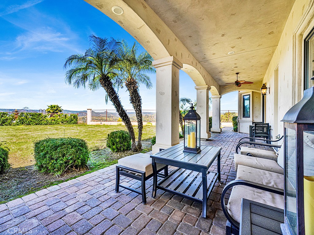 25900 Carancho Road Temecula, CA 92590 - Photo 15 of 58 a view of a patio with couches table and chairs under an umbrella next to a yard