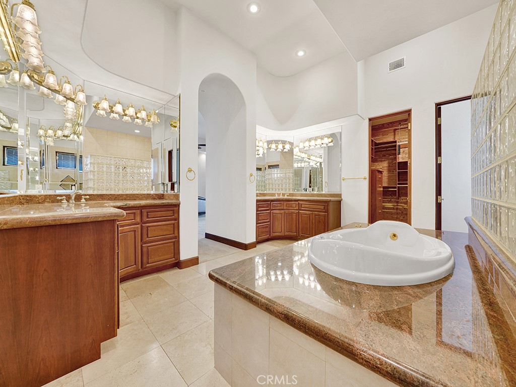 25900 Carancho Road Temecula, CA 92590 - Photo 35 of 58 a bathroom with a granite countertop sink a toilet a mirror and bathtub