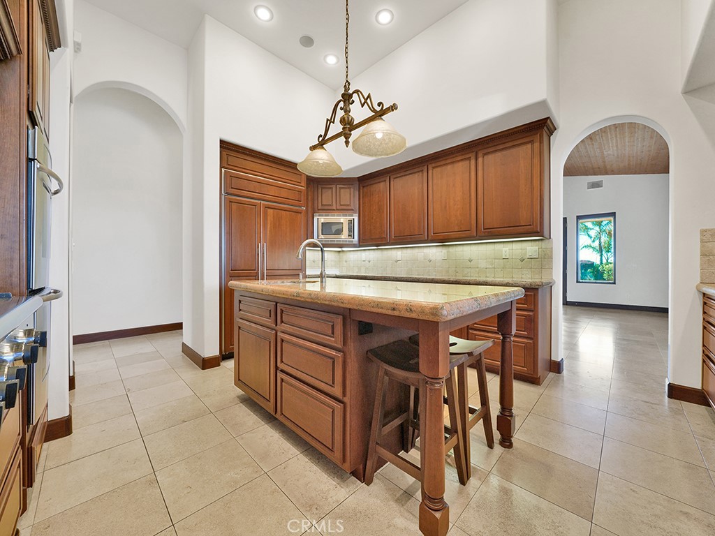 25900 Carancho Road Temecula, CA 92590 - Photo 45 of 58 a kitchen with kitchen island granite countertop a sink a stove and a refrigerator