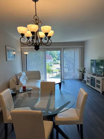 a dining room with wooden floor a chandelier a glass table and chairs