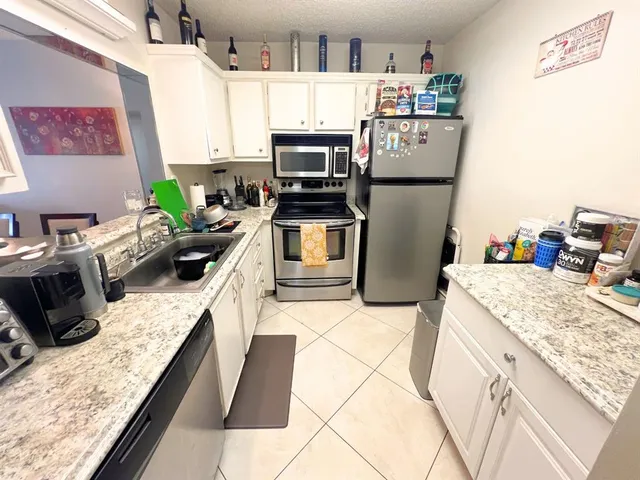a kitchen with granite countertop a refrigerator stove and sink