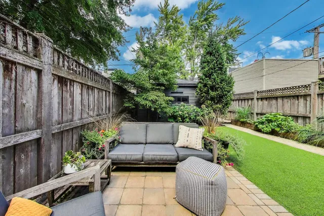 a view of a patio with couches table and chairs potted plants and large tree
