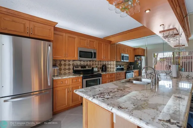 a kitchen with stainless steel appliances granite countertop a refrigerator a stove a sink a dining table and chairs