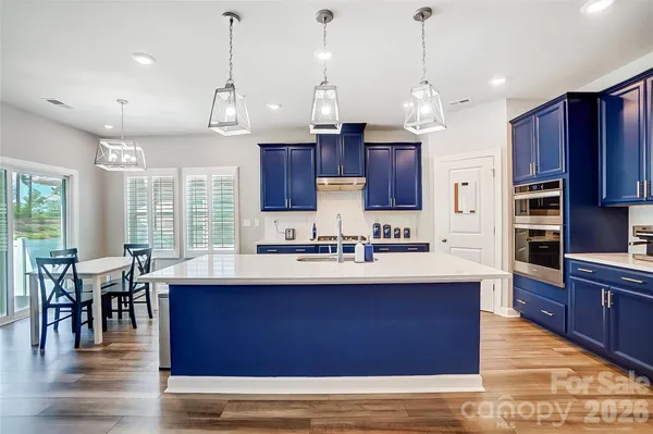 a kitchen with stainless steel appliances kitchen island granite countertop a sink stove and wooden floor