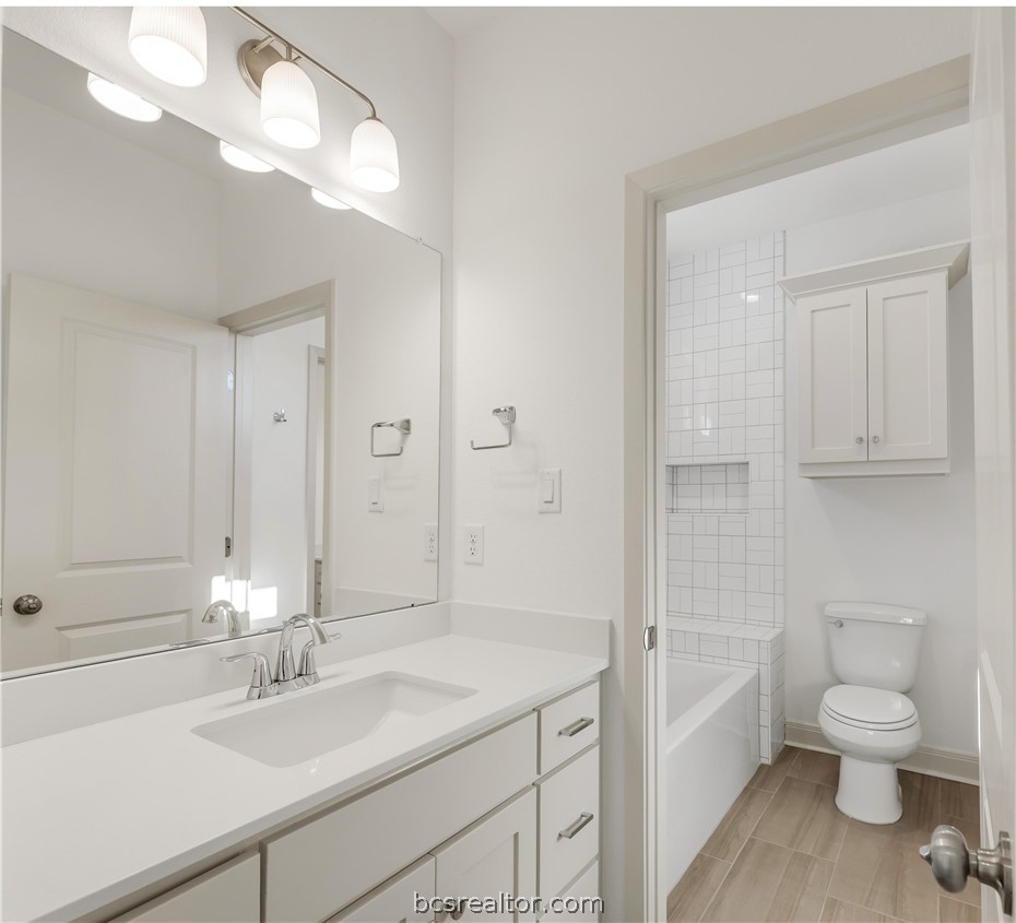 5084 Acadia Loop Bryan, TX 77802 - Photo 29 of 33 a bathroom with a granite countertop toilet a sink and a mirror