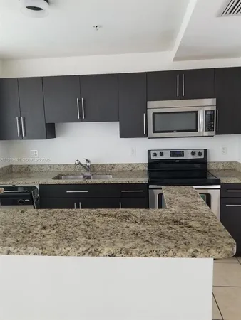 a kitchen with kitchen island granite countertop a sink and a stove