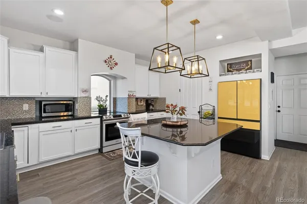 a kitchen with stainless steel appliances granite countertop a stove a sink dishwasher a dining table and chairs with wooden floor