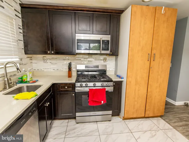 a kitchen with stainless steel appliances granite countertop a stove a sink and a microwave