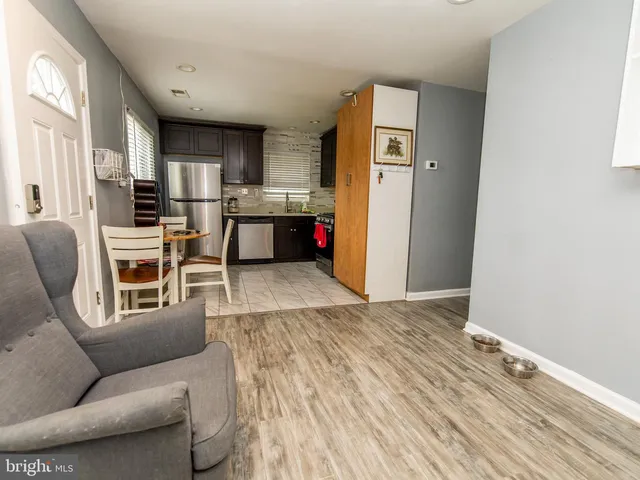 a living room with stainless steel appliances furniture a rug and a kitchen view