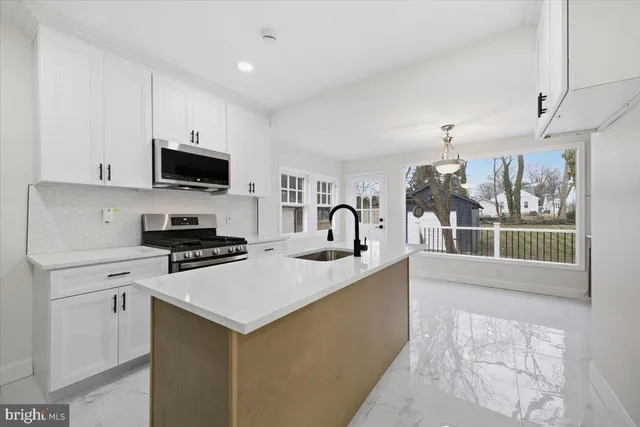 a kitchen with stainless steel appliances a stove a sink a microwave a refrigerator and cabinets