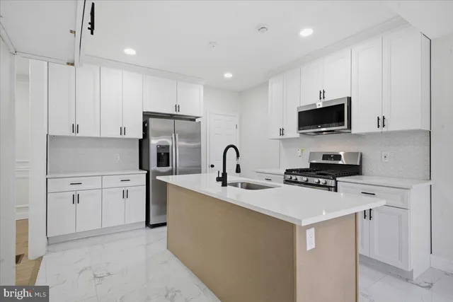 a kitchen with stainless steel appliances granite countertop a stove top oven a sink a refrigerator and white cabinets