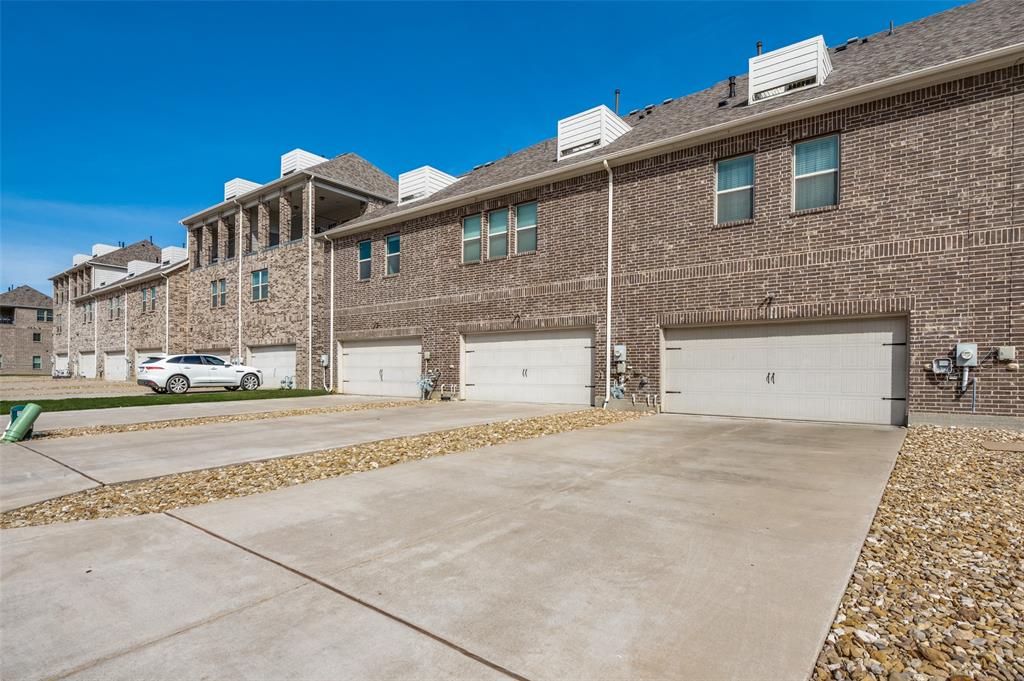 1560 Windermere Way Dallas, TX 75234 - Photo 25 of 25 Rear view of house with an attached garage, brick siding, and concrete driveway