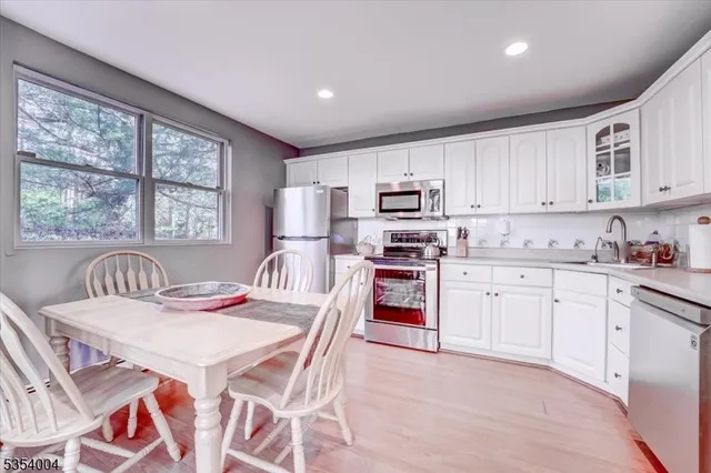 a kitchen with stainless steel appliances granite countertop a stove a sink a microwave a refrigerator with a dining table and chairs