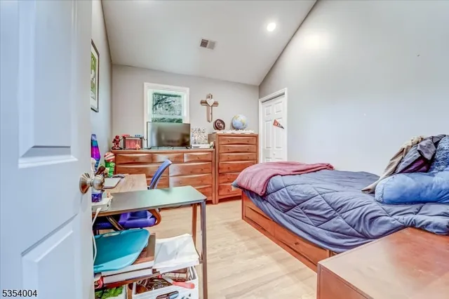a bedroom with two beds and a dresser next to a window
