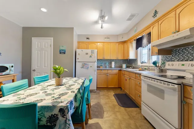 a kitchen with granite countertop kitchen island a stove a sink a dining table and chairs