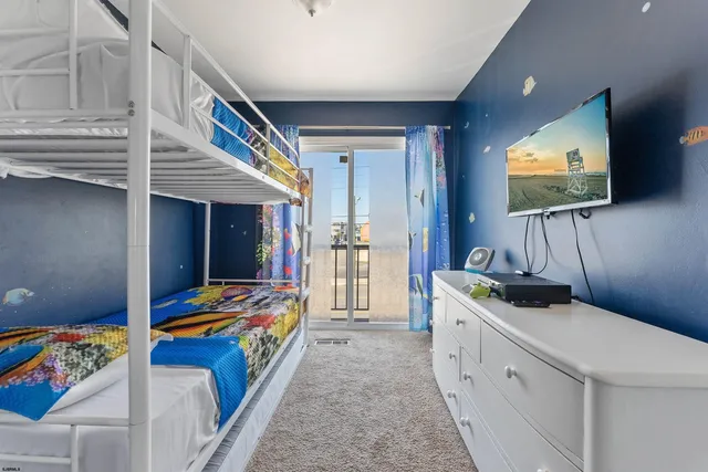 a bedroom with bed and a flat tv screen on dresser