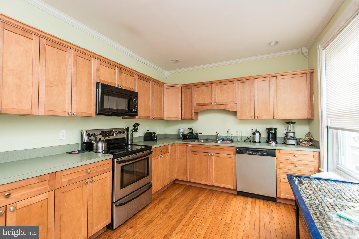 133 Dupont Street Philadelphia, PA 19127 - Photo 3 of 24 a kitchen with granite countertop wooden floors stainless steel appliances a sink and a window