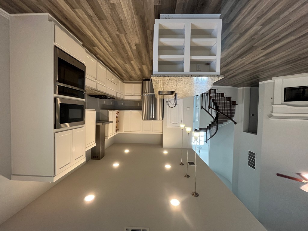 121 Red Granite Road Georgetown, TX 78633 - Photo 8 of 23 Kitchen with white cabinets, a fireplace with raised hearth, hanging light fixtures, stainless steel appliances, and light stone counters