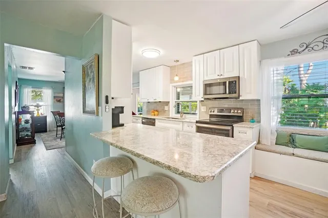 a large kitchen with granite countertop a stove a sink a dining table and chairs