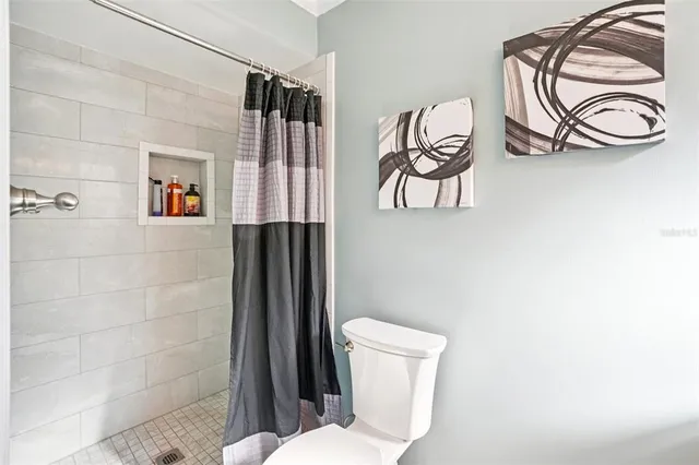 a bathroom with a toilet and a painting on the wall