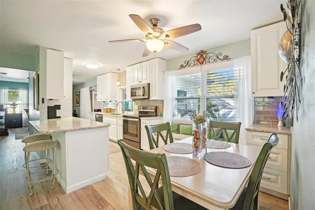 a dining room with stainless steel appliances a table and chairs with wooden floor