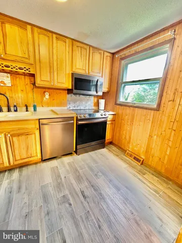 a kitchen with stainless steel appliances granite countertop a sink a stove cabinets and wooden floor