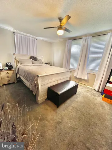 a spacious bedroom with a bed a chandelier and a large window