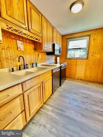 a kitchen with stainless steel appliances granite countertop a sink cabinets and wooden floor