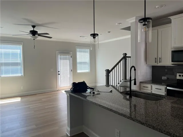 a living room with stainless steel appliances kitchen island granite countertop furniture a sink a window and wooden floor