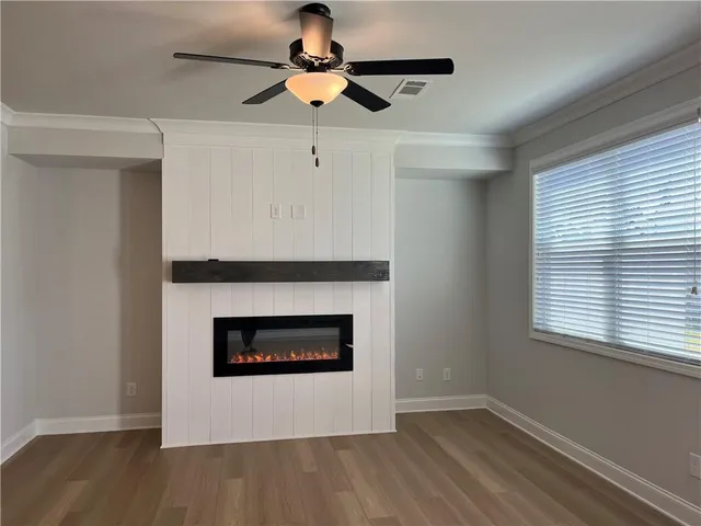 a living room with a fireplace a ceiling fan and wooden floor