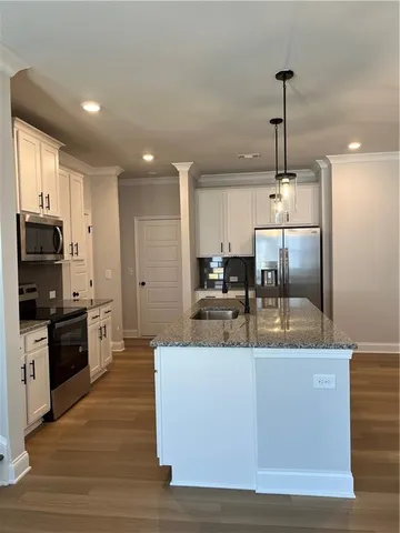 a large kitchen with kitchen island a large counter top stainless steel appliances and cabinets