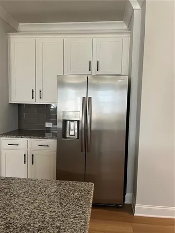 a kitchen with a refrigerator and white cabinets