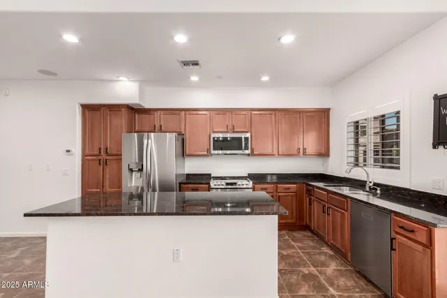 a kitchen with stainless steel appliances granite countertop a refrigerator a sink a stove a microwave and island