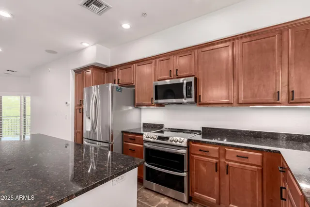 a large kitchen with stainless steel appliances a refrigerator and a stove top oven