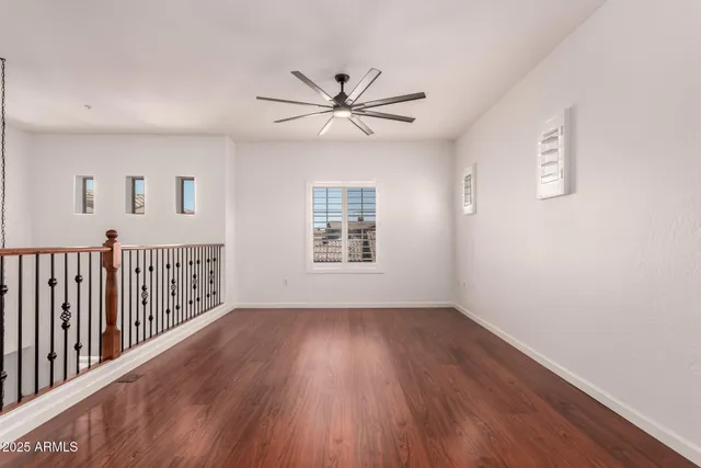 an empty room with wooden floor fan and windows