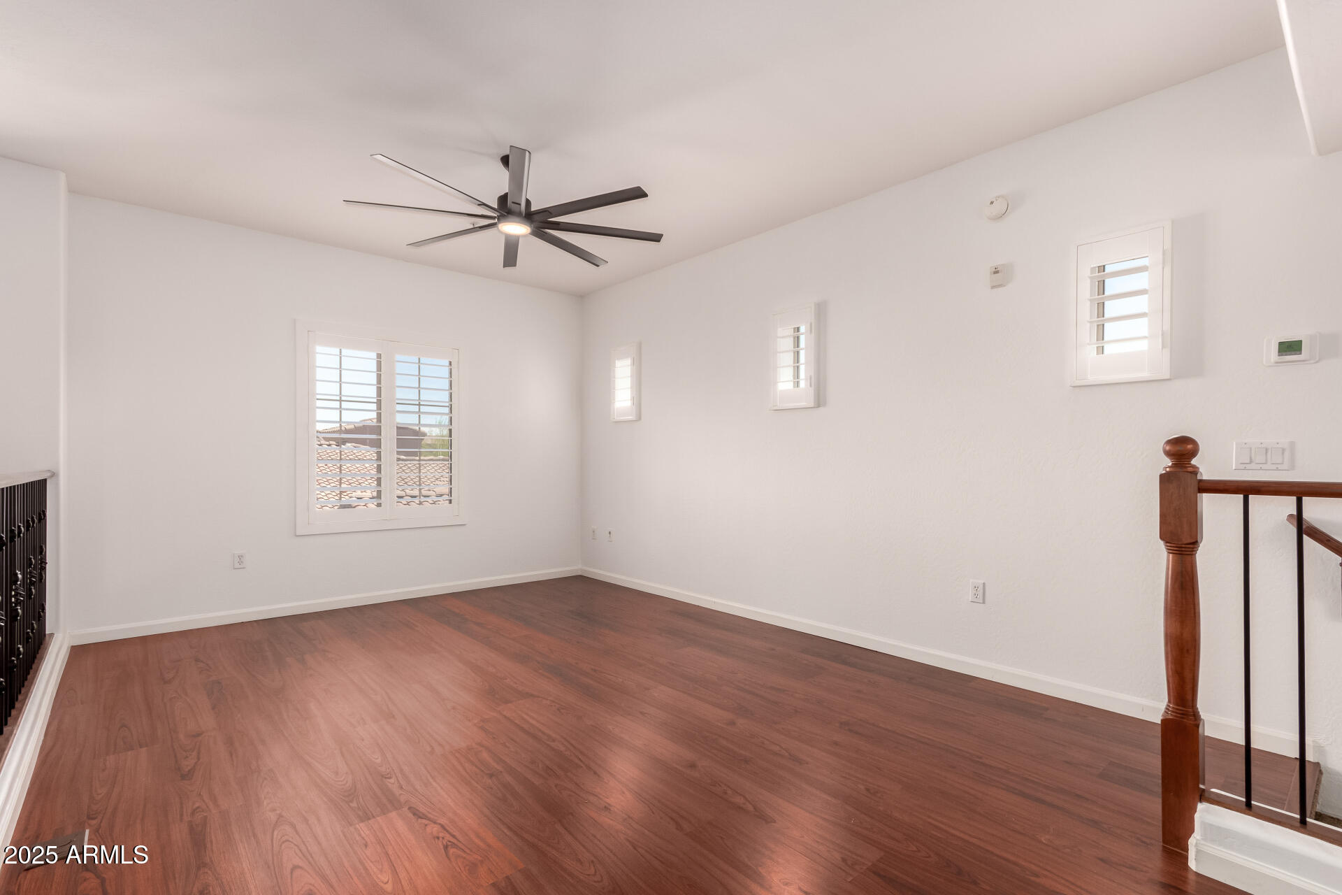 3935 East Rough Rider Road, Unit 1076 Phoenix, AZ 85050 - Photo 28 of 48 an empty room with wooden floor fan and windows