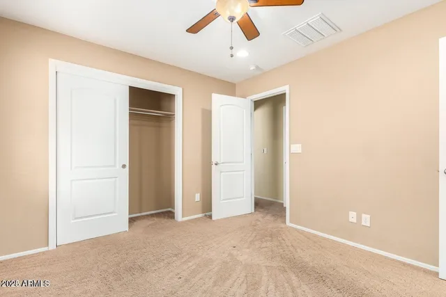 an empty room with closet and a ceiling fan