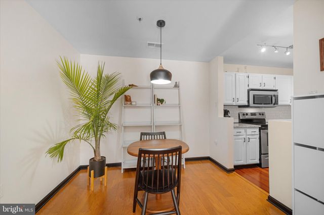 a kitchen with stainless steel appliances a dining table chairs stove refrigerator and cabinets