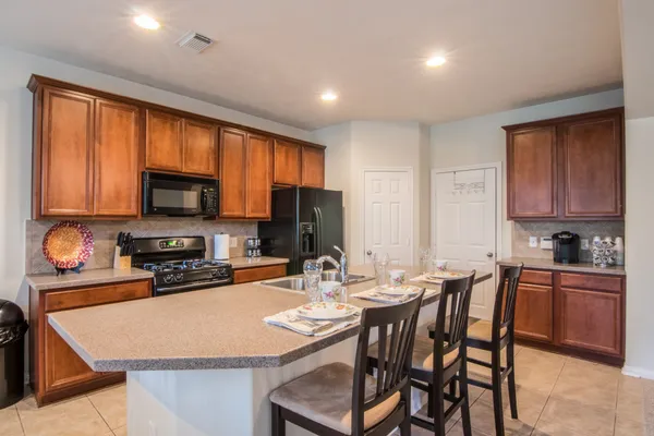 a kitchen with stainless steel appliances granite countertop a stove top oven a sink dishwasher a dining table and chairs with wooden floor