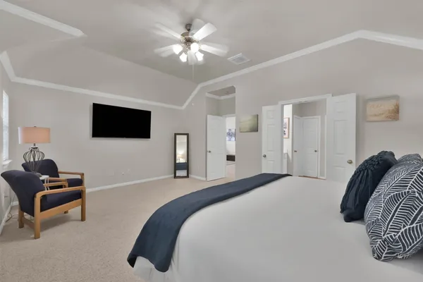 a bedroom with a bed a flat screen tv and a chandelier