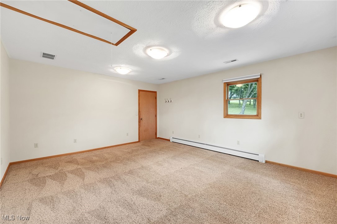 7923 Zigler Road Sterling, OH 44276 - Photo 14 of 31 Carpeted empty room with a baseboard heating unit and attic access