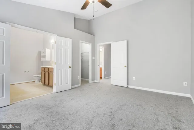 an empty room with chandelier fan and windows